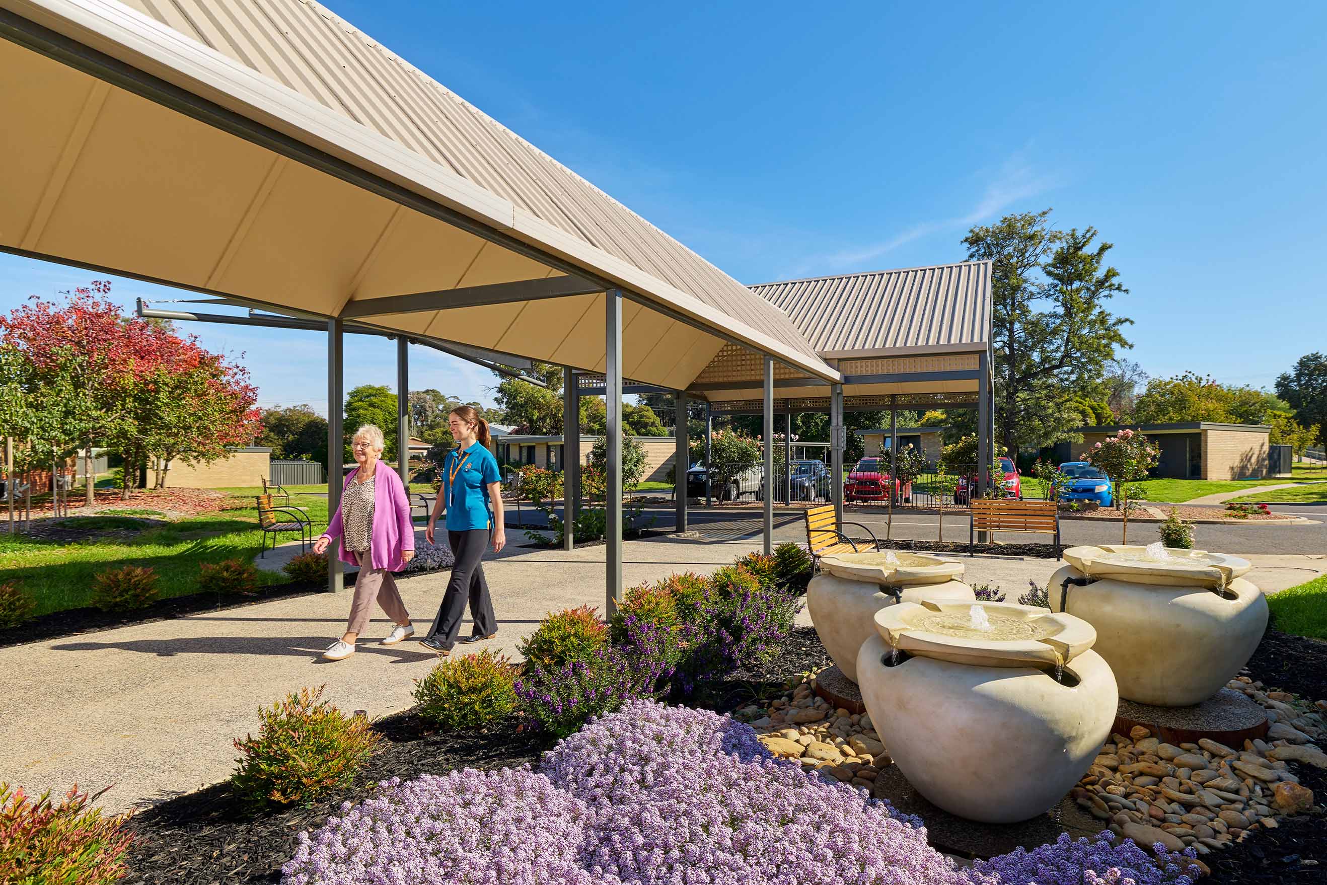 Resident and Benetas team member walking through the landscaped entrance gardens at Benetas Eaglehawk