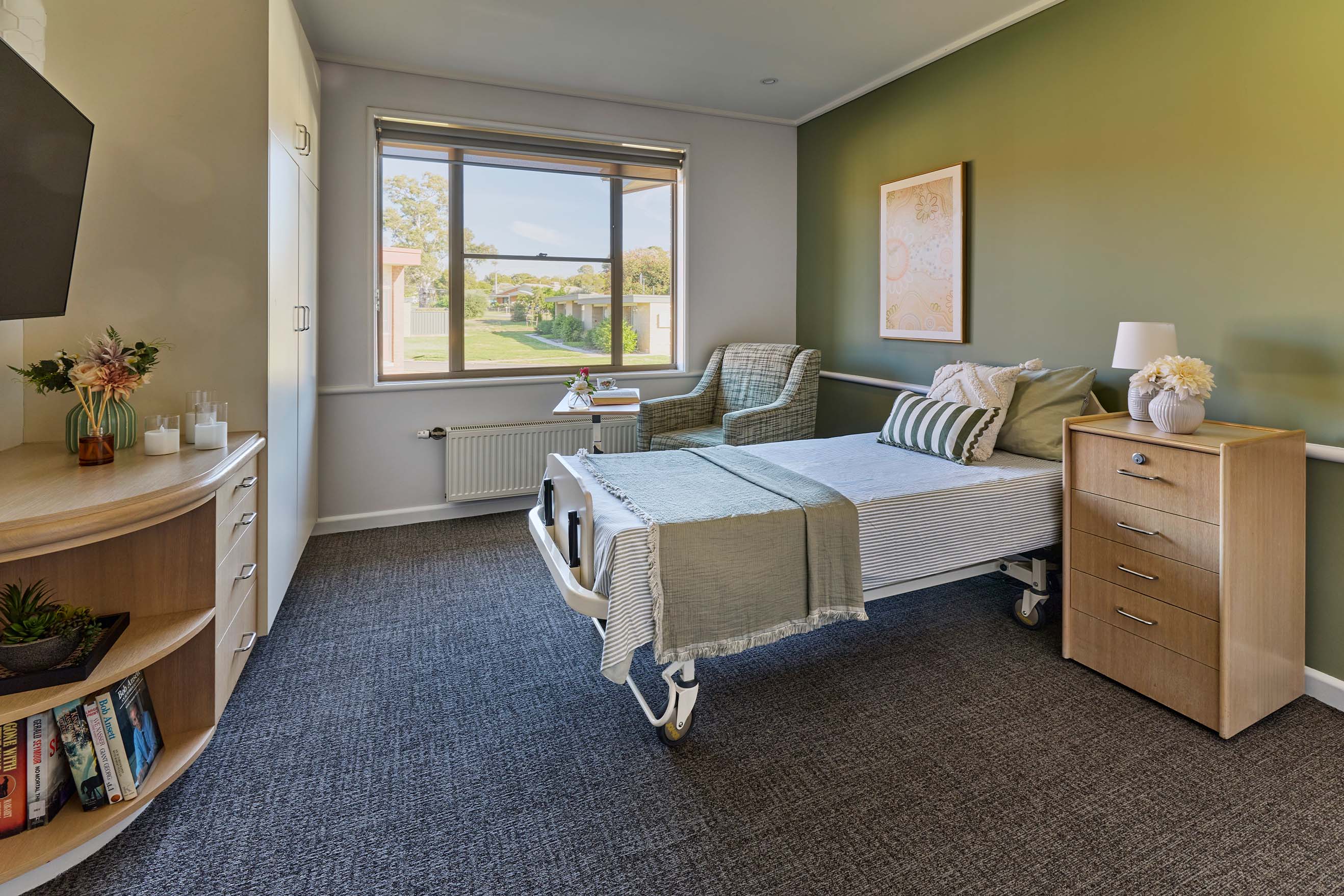 Bright private resident room with bed, armchair, storage and garden view at Benetas Eaglehawk