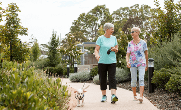 Two women walking their dog on a scenic path at St Laurence Court
