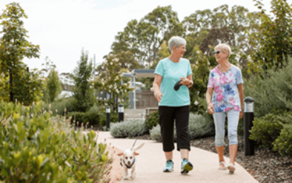 Two women walking their dog on a scenic path at St Laurence Court