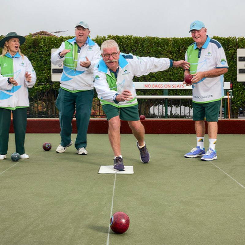 A group of people playing bowls on a green field.