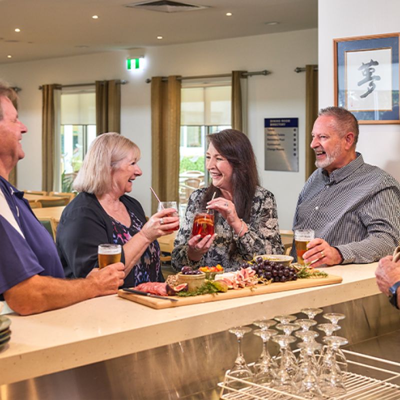 A diverse group of individuals happily together at happy hour, savoring delicious food and engaging in lively conversations.