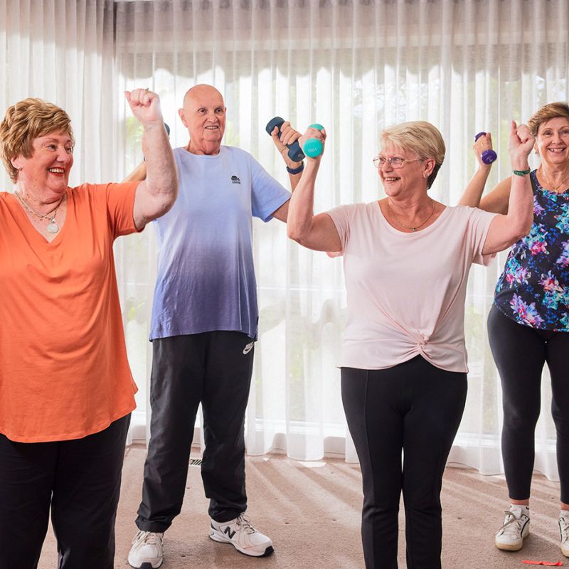 A diverse group of older individuals engaging in a workout routine, lifting dumbbells to maintain their physical fitness.