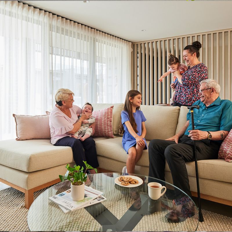 A family of four sitting on a cozy couch in a well-decorated living room, enjoying each other's company.